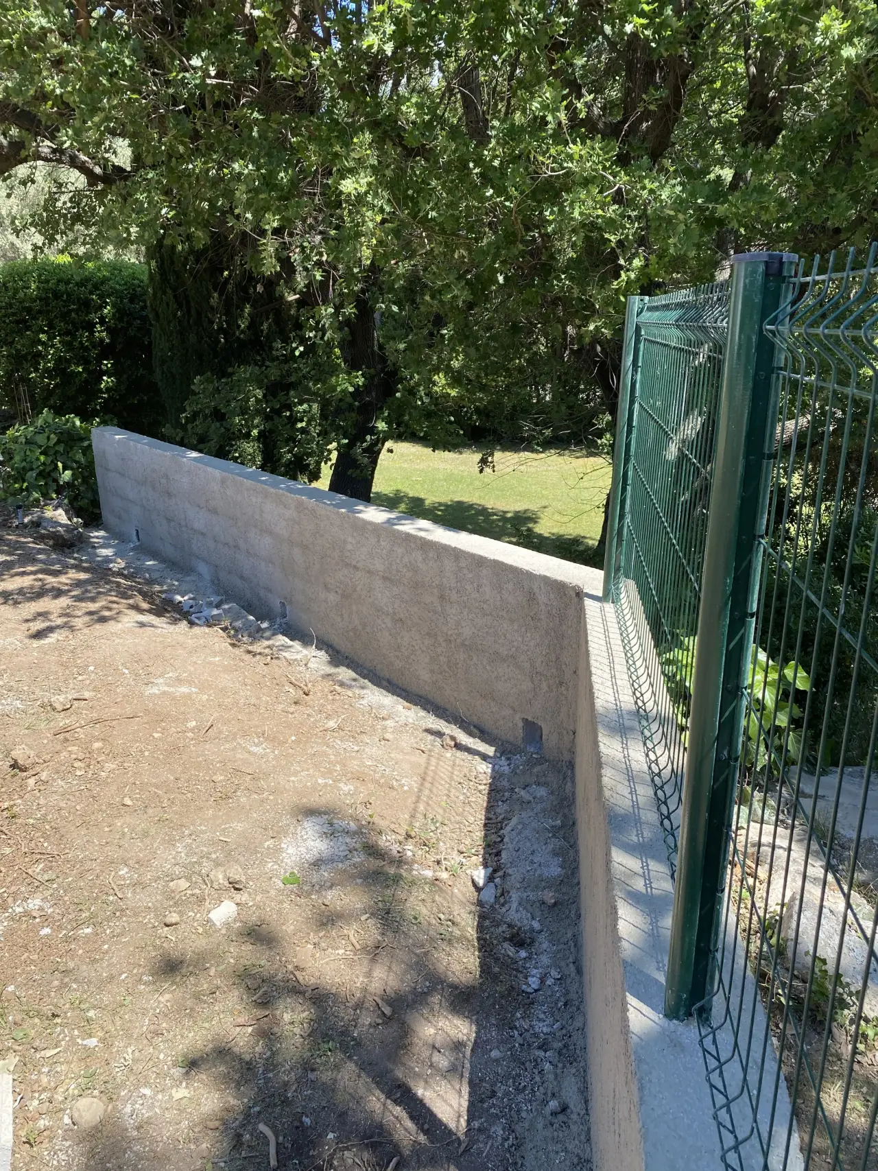 Mur de clôture enduit le long d'un grillage