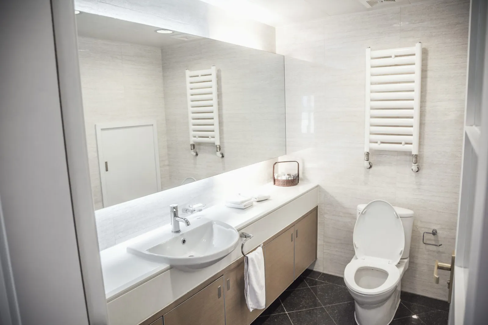 Salle de bain blanche avec sèche-serviettes et WC suspendu