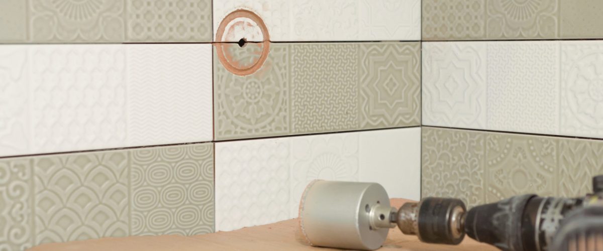 Preparatory work for the installation of an electrical outlet, building tools, tile cutter, grinder in the process of drilling tiles. Round hole in the ceramic tile.