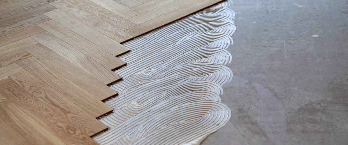 A worker laying parquet flooring and installing wooden laminate